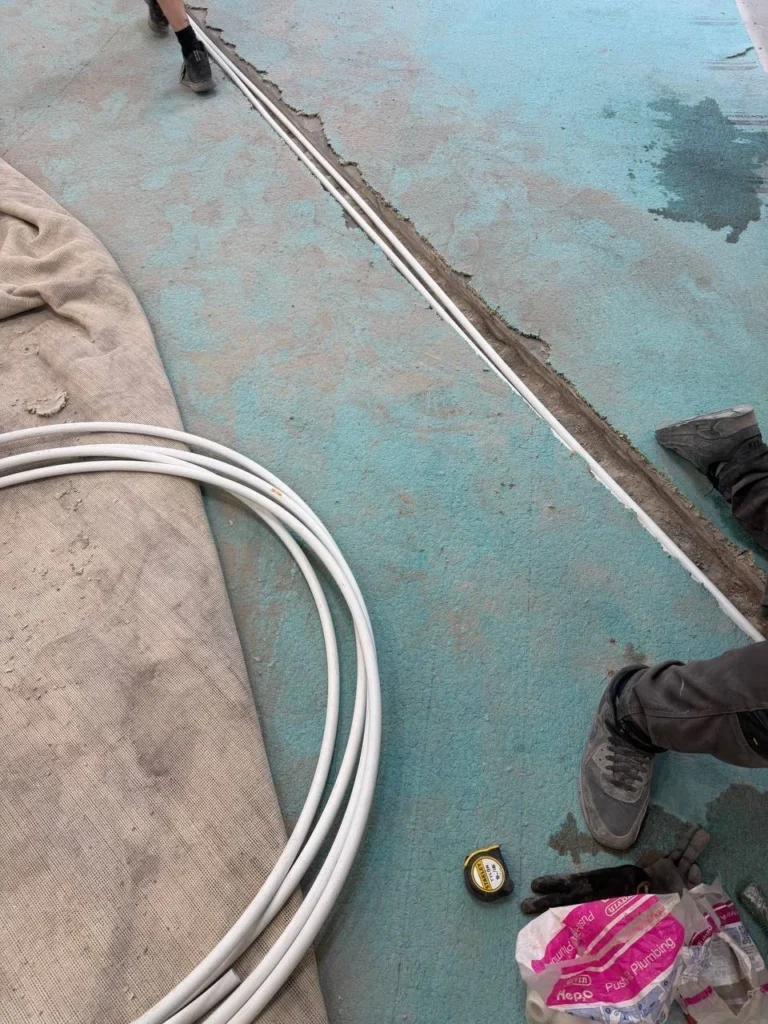 New heating pipes laid in channels cut into the floor.