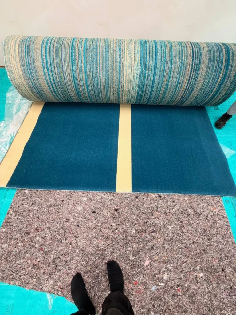 The first roll of the new carpet going down over the new underlay.
